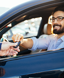 man sitting in driver's seat getting handed keys